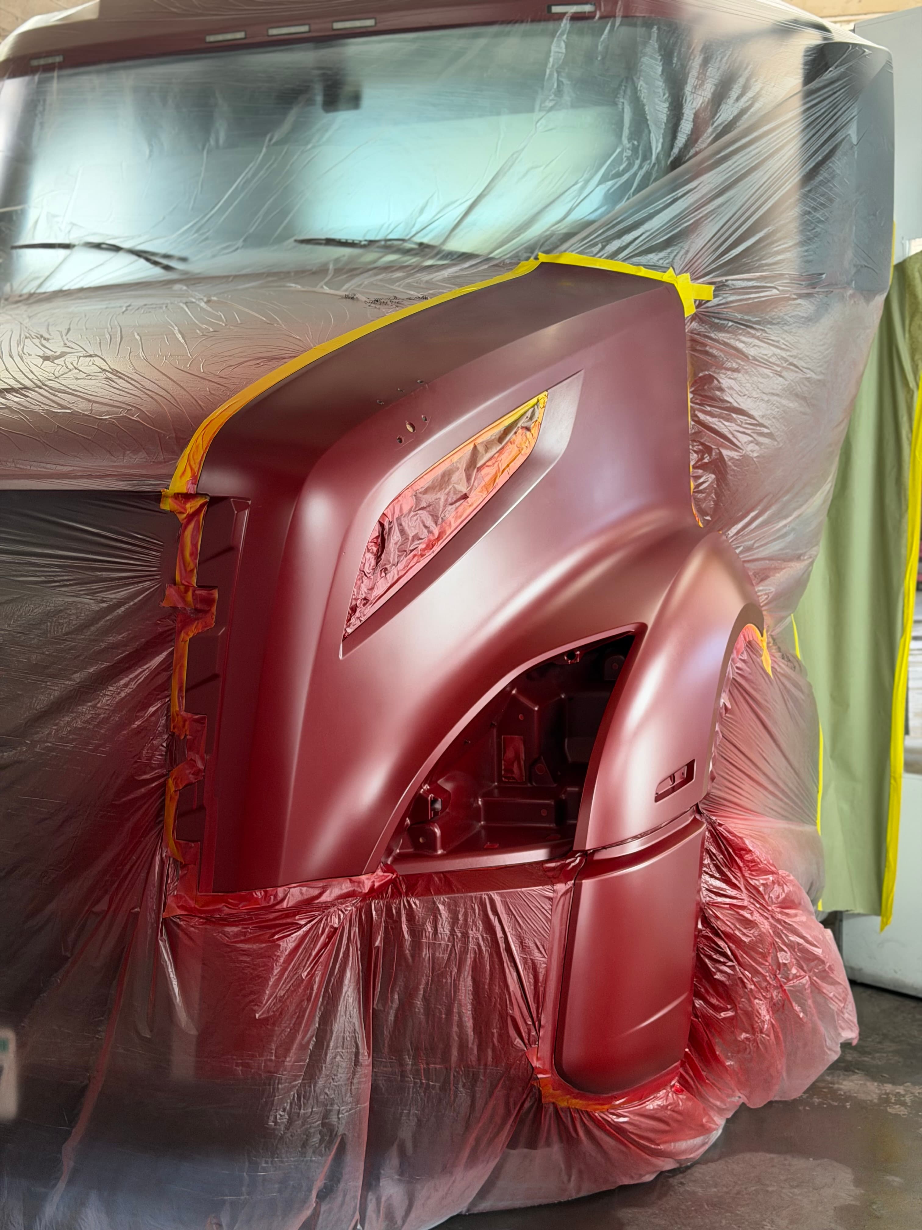Commercial semi truck front fender and hood with fresh red paint in the paint booth at D&S Auto Repair in Vallejo, CA